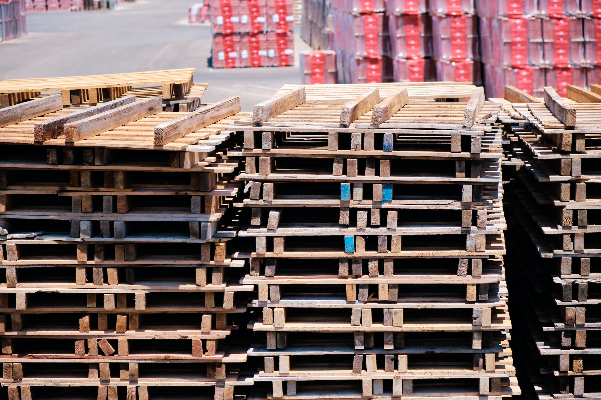 Wooden pallets stacked on a forecourt outside a factory.